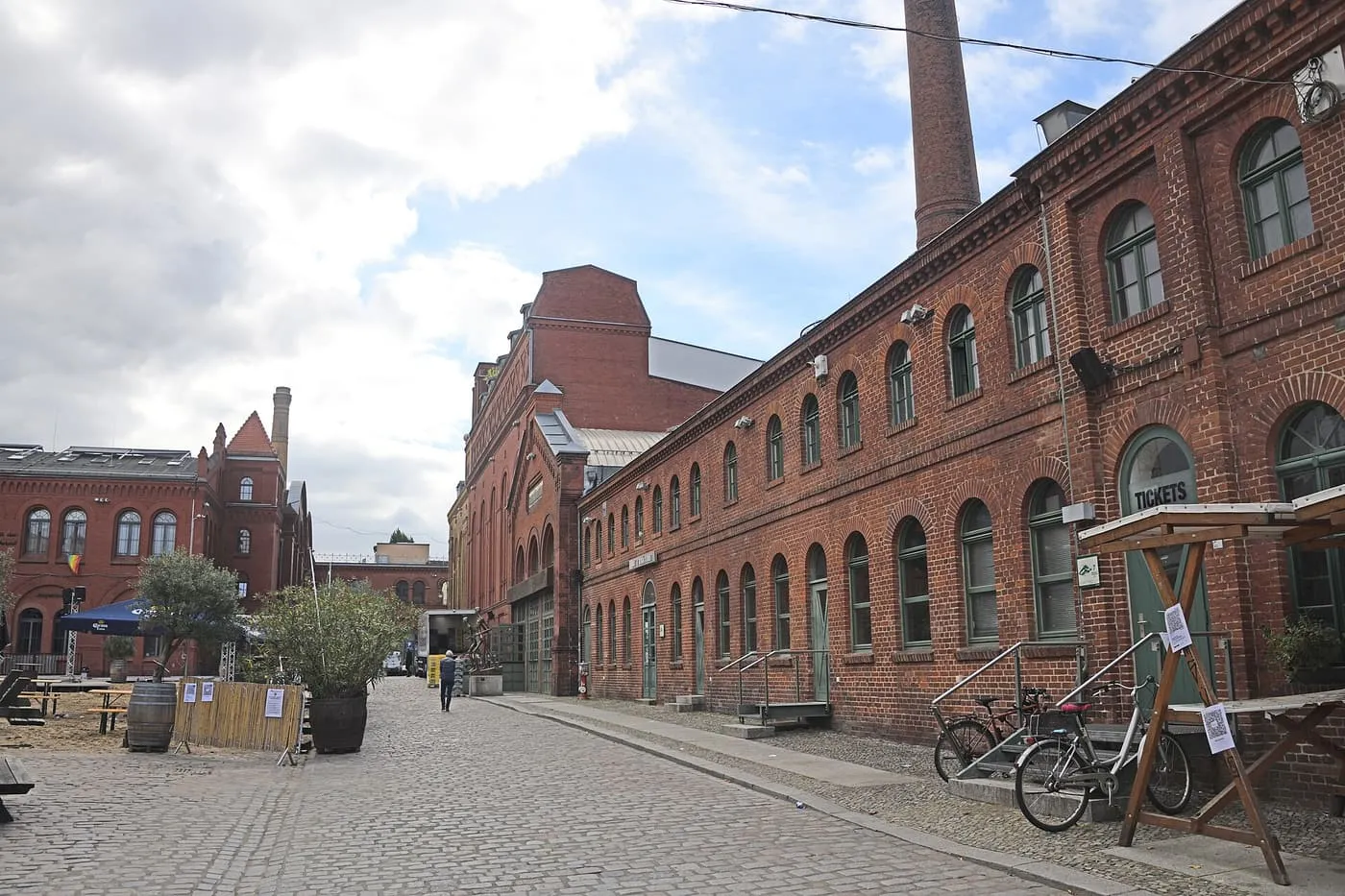 The long red-brick facade and chimney of the former brewery buildings of the Kulturbrauerei, seen from a cobbled courtyard