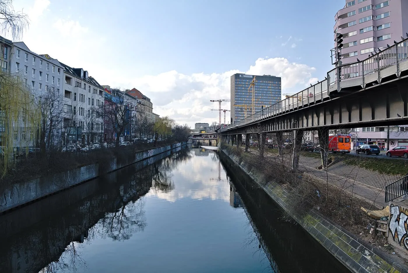 The still water of the Landwehr Canal between apartment blocks on one bank and the U-Bahn viaduct on the other