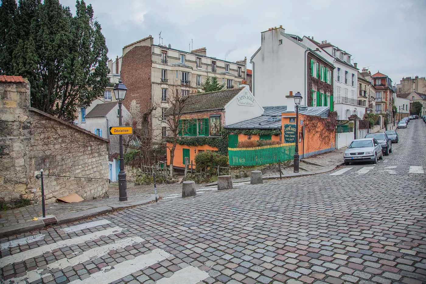 The orange walls and green shutters of the Lapin Agile cabaret on the corner of rue des Saules and rue Saint-Vincent