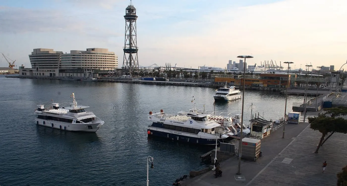 Las Golondrinas harbour boats on the water and at their quay in Port Vell, with the World Trade Center and the port cable-car tower behind