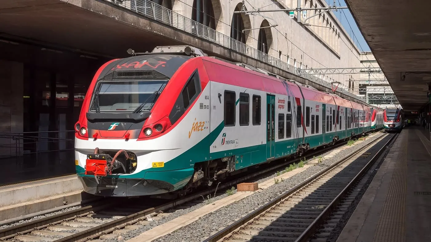 A red, white and green Leonardo Express train at a platform at Roma Termini