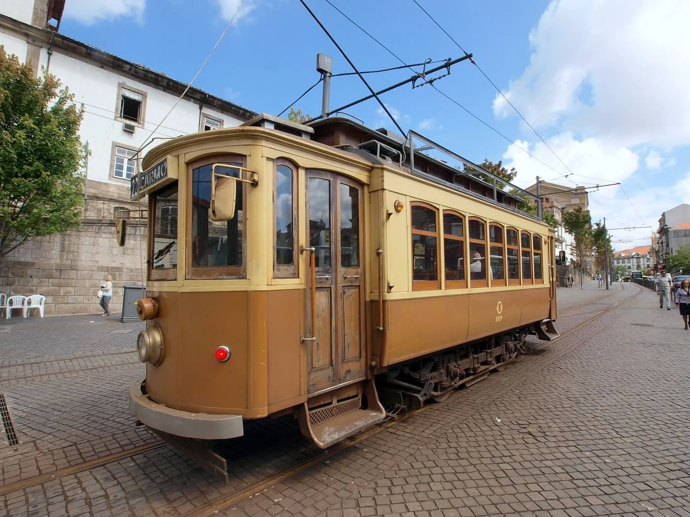 A cream and brown historic Porto tram marked 22 Carmo on a cobbled street, with overhead wires and old buildings behind