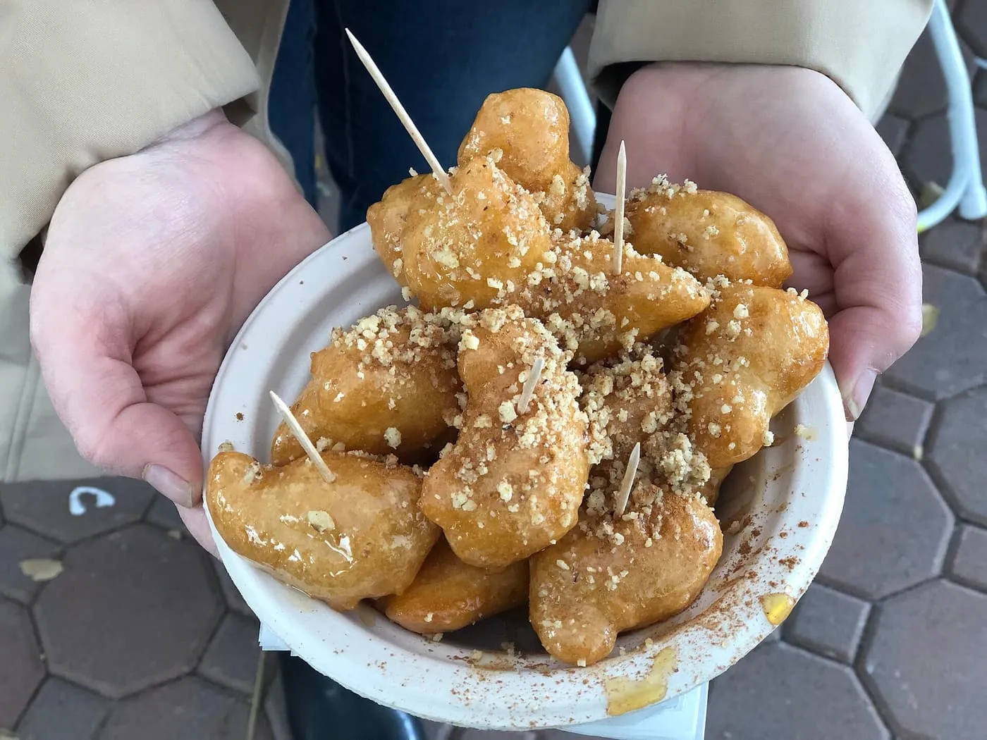 A bowl of loukoumades, fried dough balls glazed with honey and sprinkled with chopped walnuts and cinnamon