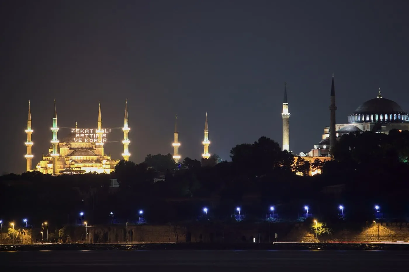 The Blue Mosque and Hagia Sophia at night, with a mahya, a message in lights, strung between the Blue Mosque minarets