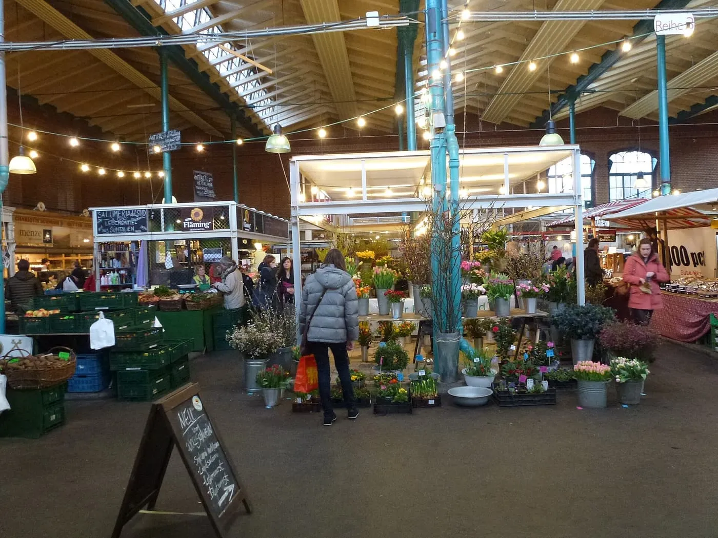 Flower and produce stalls under the timber roof and iron columns of Markthalle Neun