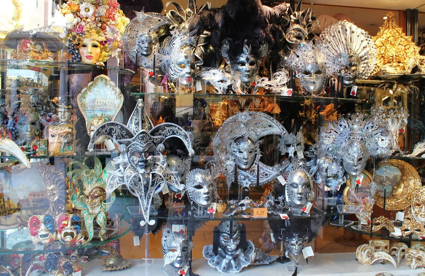 A shop window crowded with silver, gold and painted Venetian masks