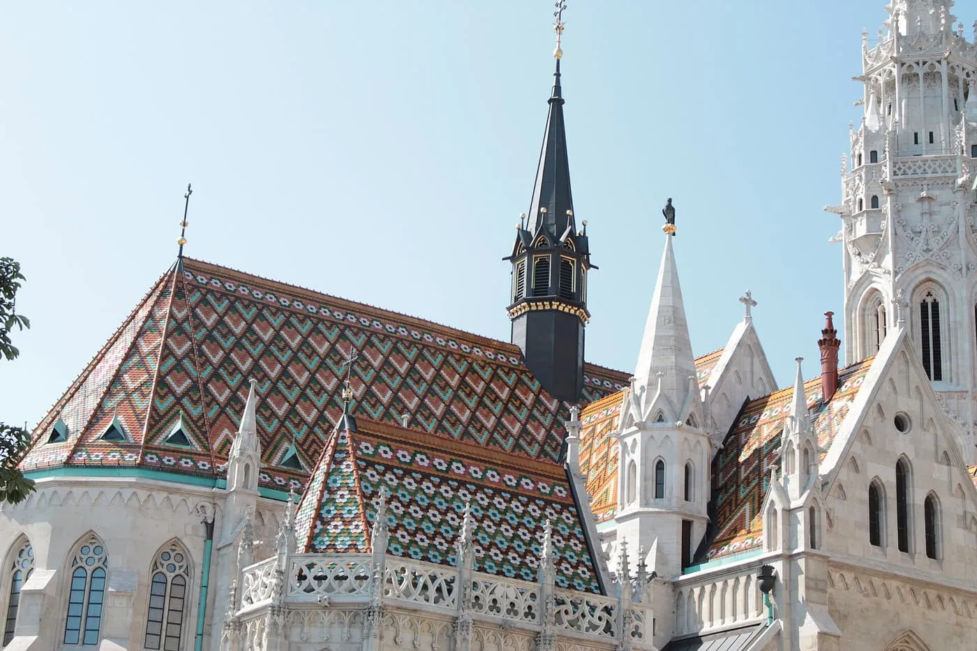The steep roof of Matthias Church patterned in coloured glazed tiles, beside its white stone spire