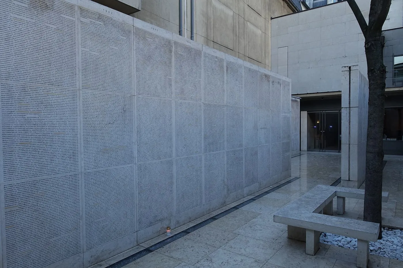 The Wall of Names at the Mémorial de la Shoah, a long pale stone wall engraved with rows of names in a courtyard