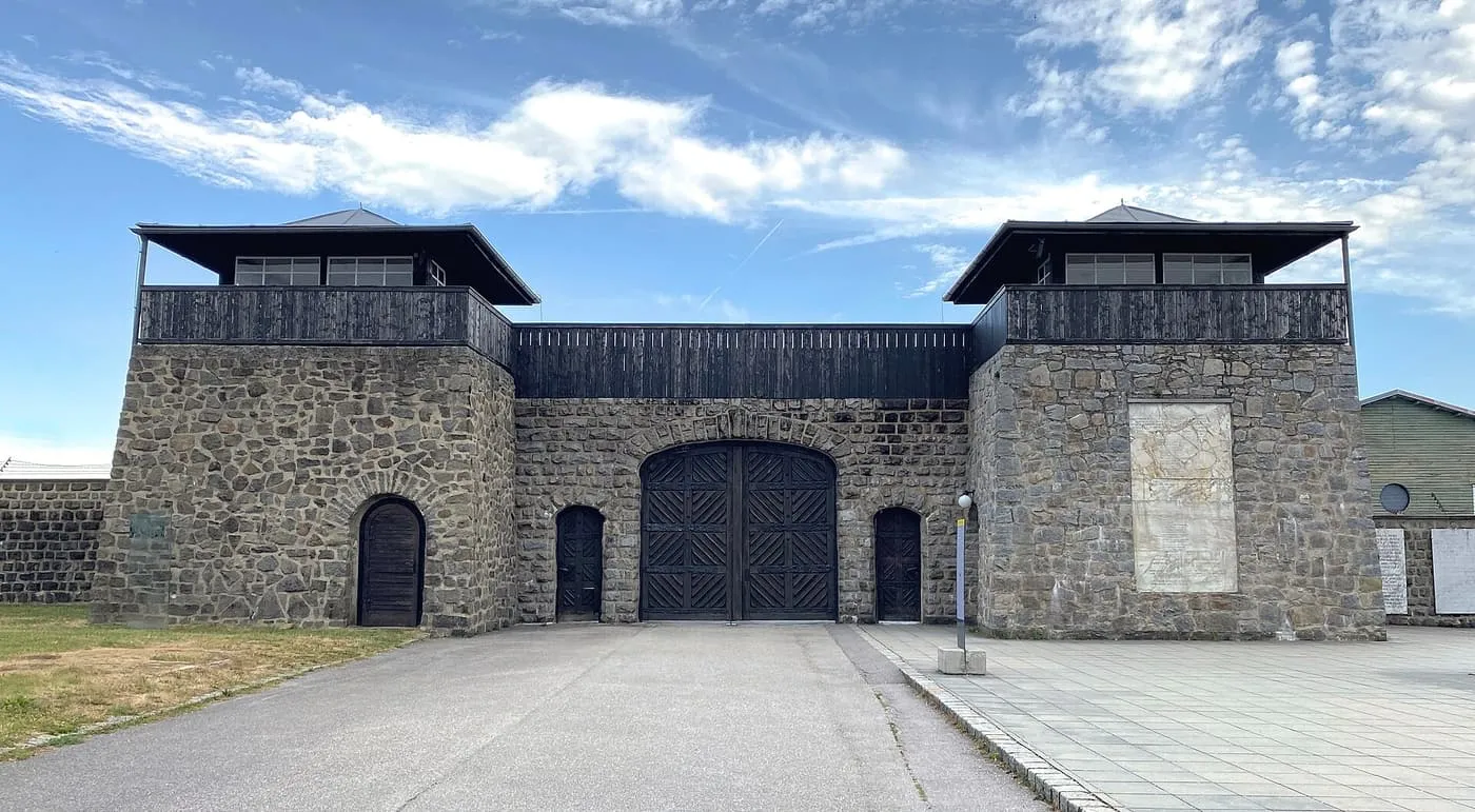 The stone gatehouse of the Mauthausen Memorial, with two watchtowers and a dark wooden gate