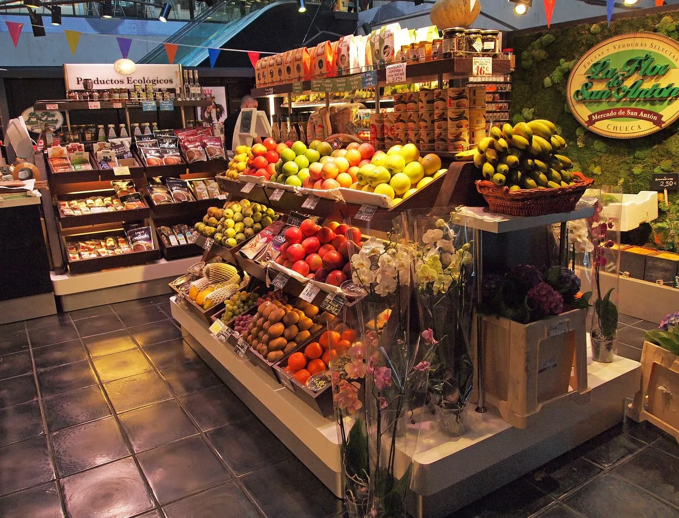 A fruit stall piled with apples, kiwis, oranges and bananas inside the Mercado de San Antón in Chueca