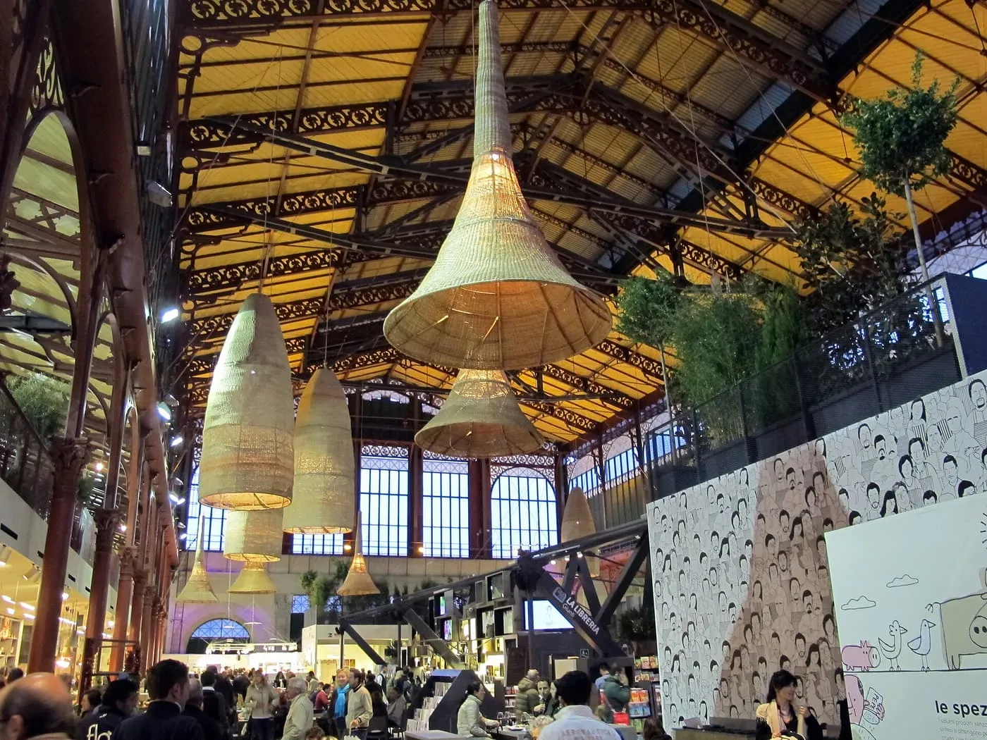 The iron and glass roof of the Mercato Centrale hall, with woven lampshades hanging above the food-hall tables