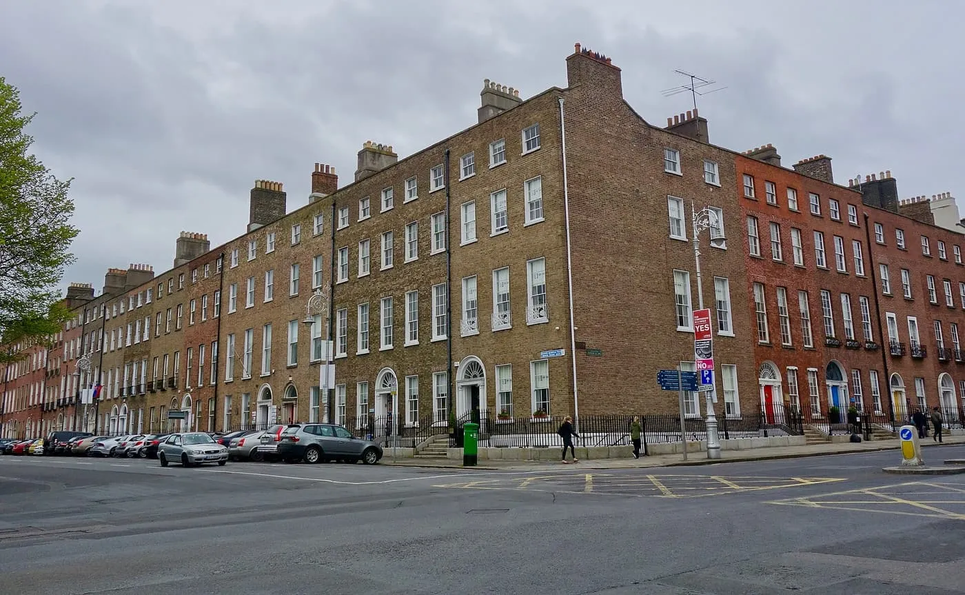 A long terrace of Georgian brick townhouses with coloured front doors on the corner of Merrion Square