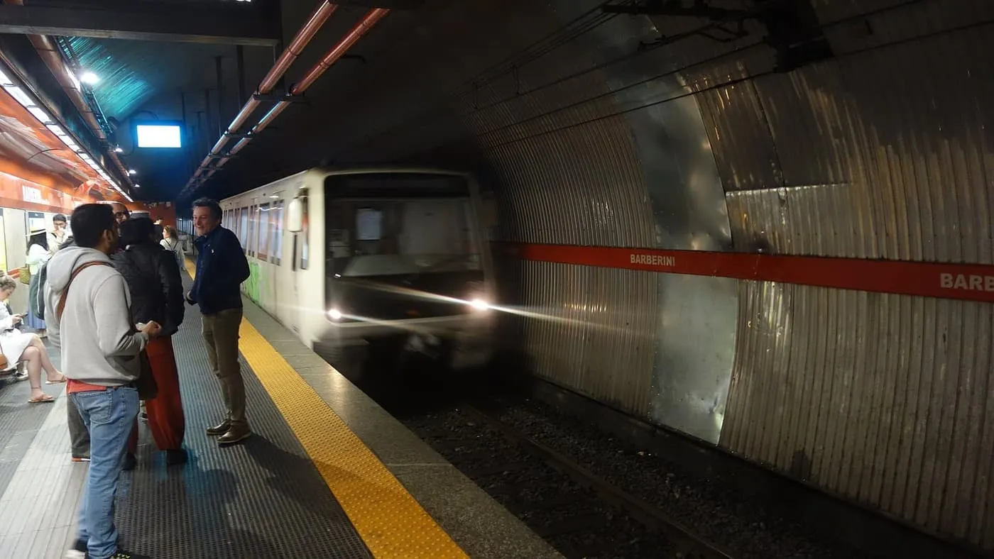 A metro train pulling into Barberini station on Rome's Line A, with passengers waiting on the platform