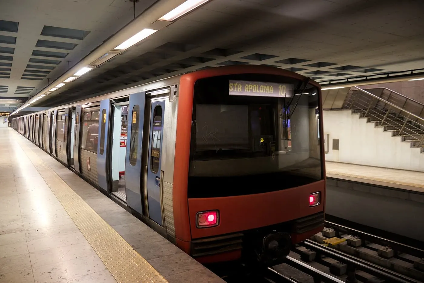 A red Metro train with Sta Apolónia on its destination blind waiting at a platform