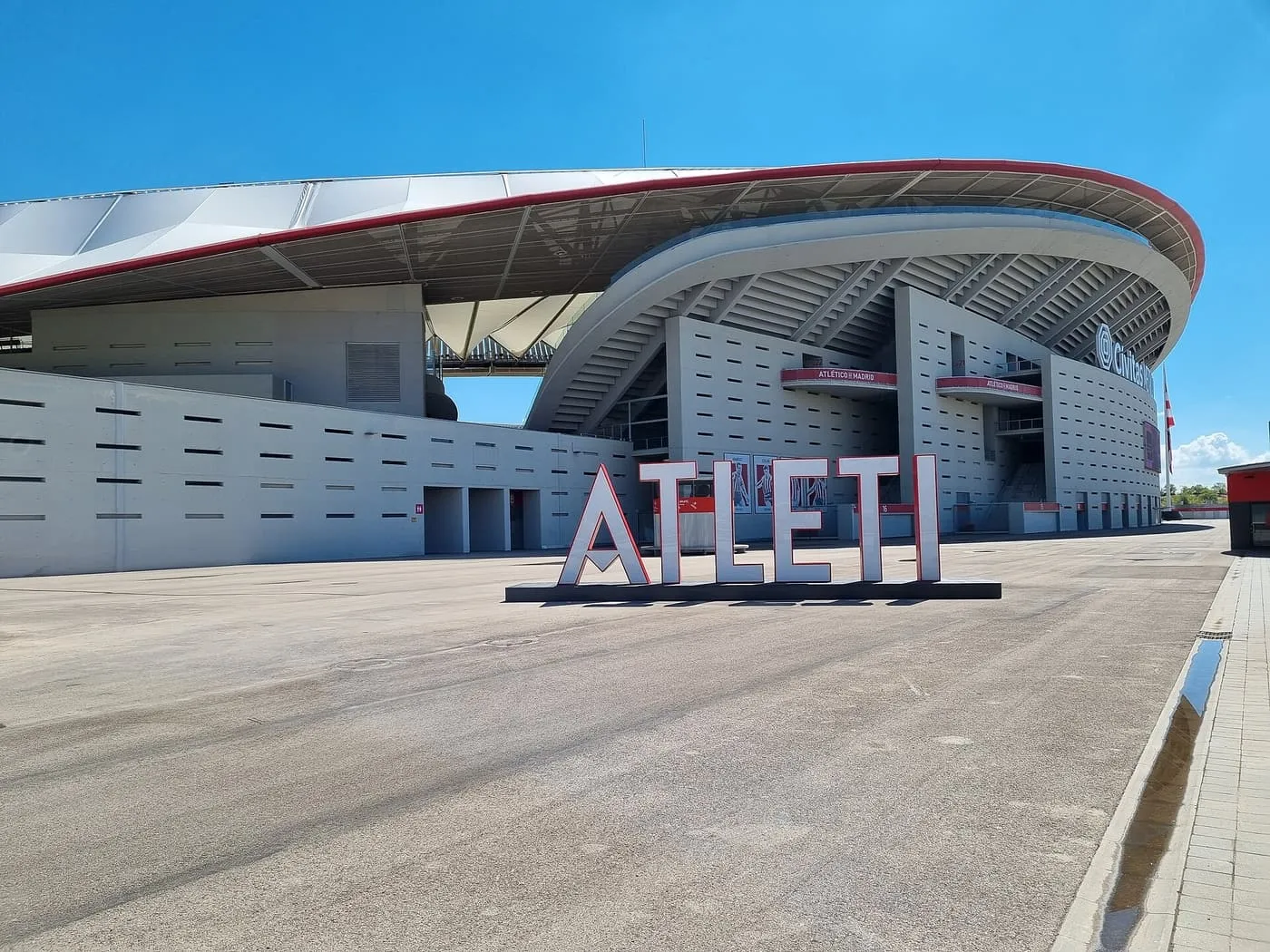 The outside of Atlético de Madrid's Metropolitano stadium, with its curved concrete walls, red-edged roof and large ATLETI letters on the forecourt