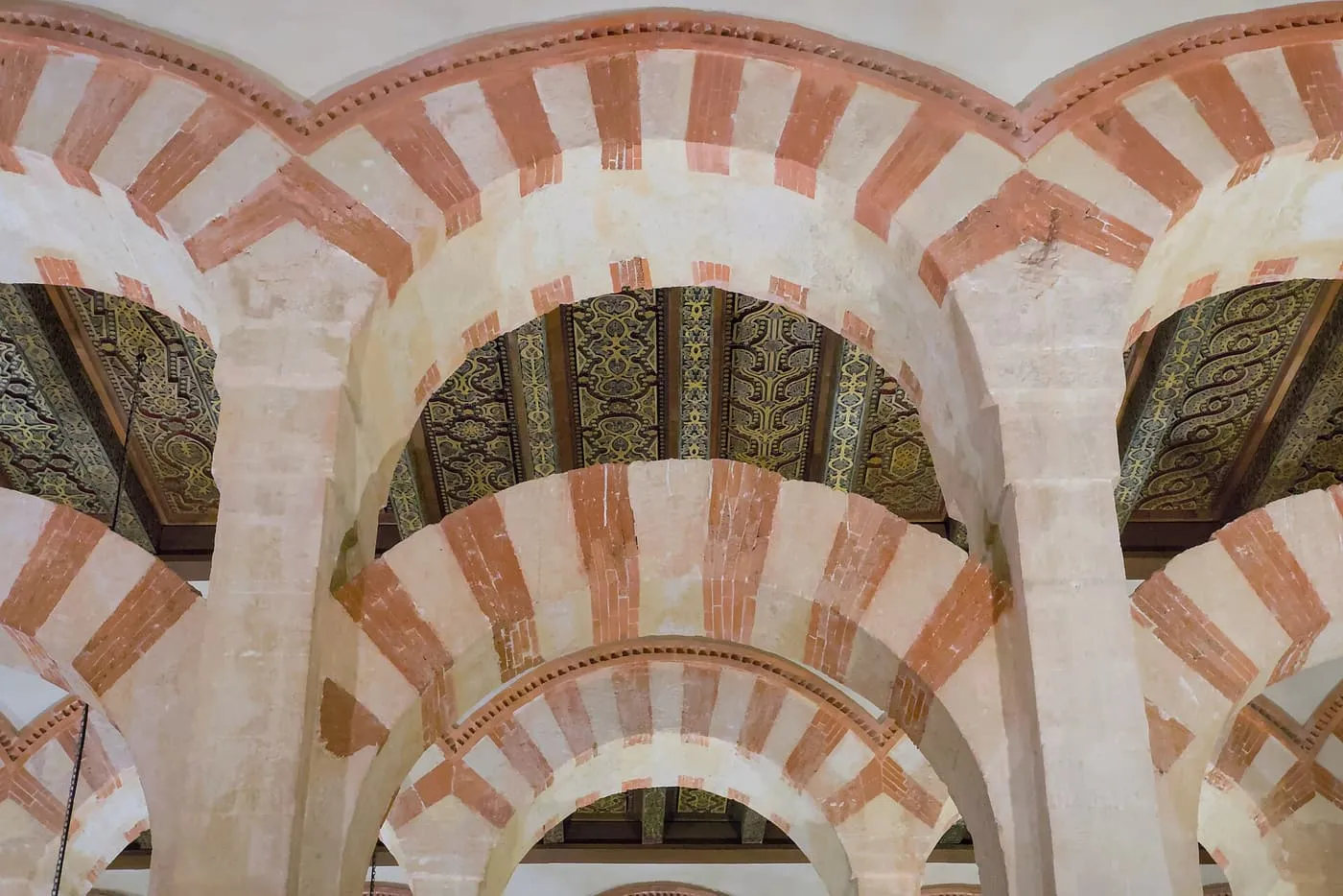 Red-and-white striped arches in the Mezquita-Catedral, with the painted wooden ceiling visible between them