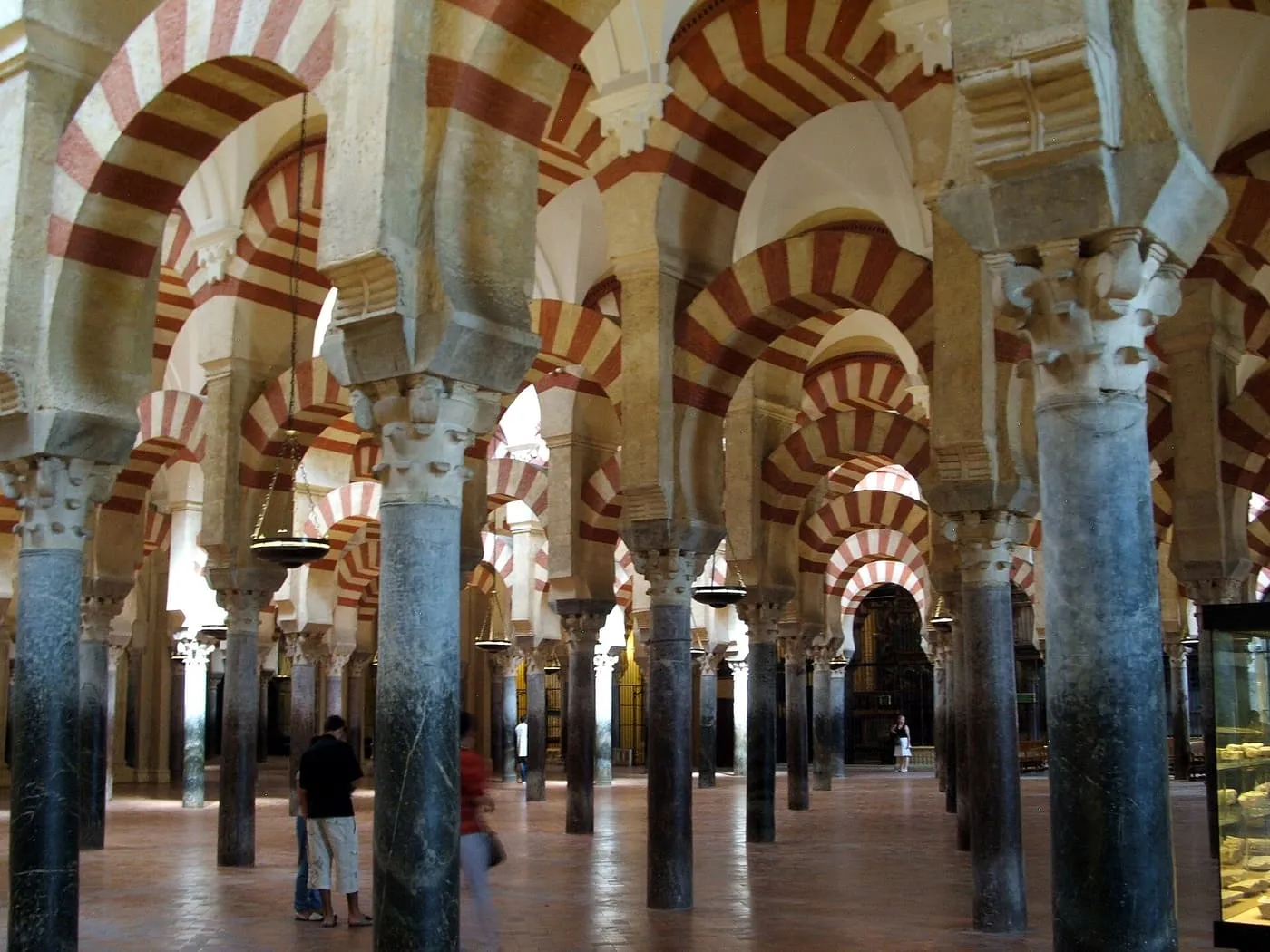 Rows of columns carrying double tiers of red-and-white striped arches in the prayer hall of the Mezquita-Catedral