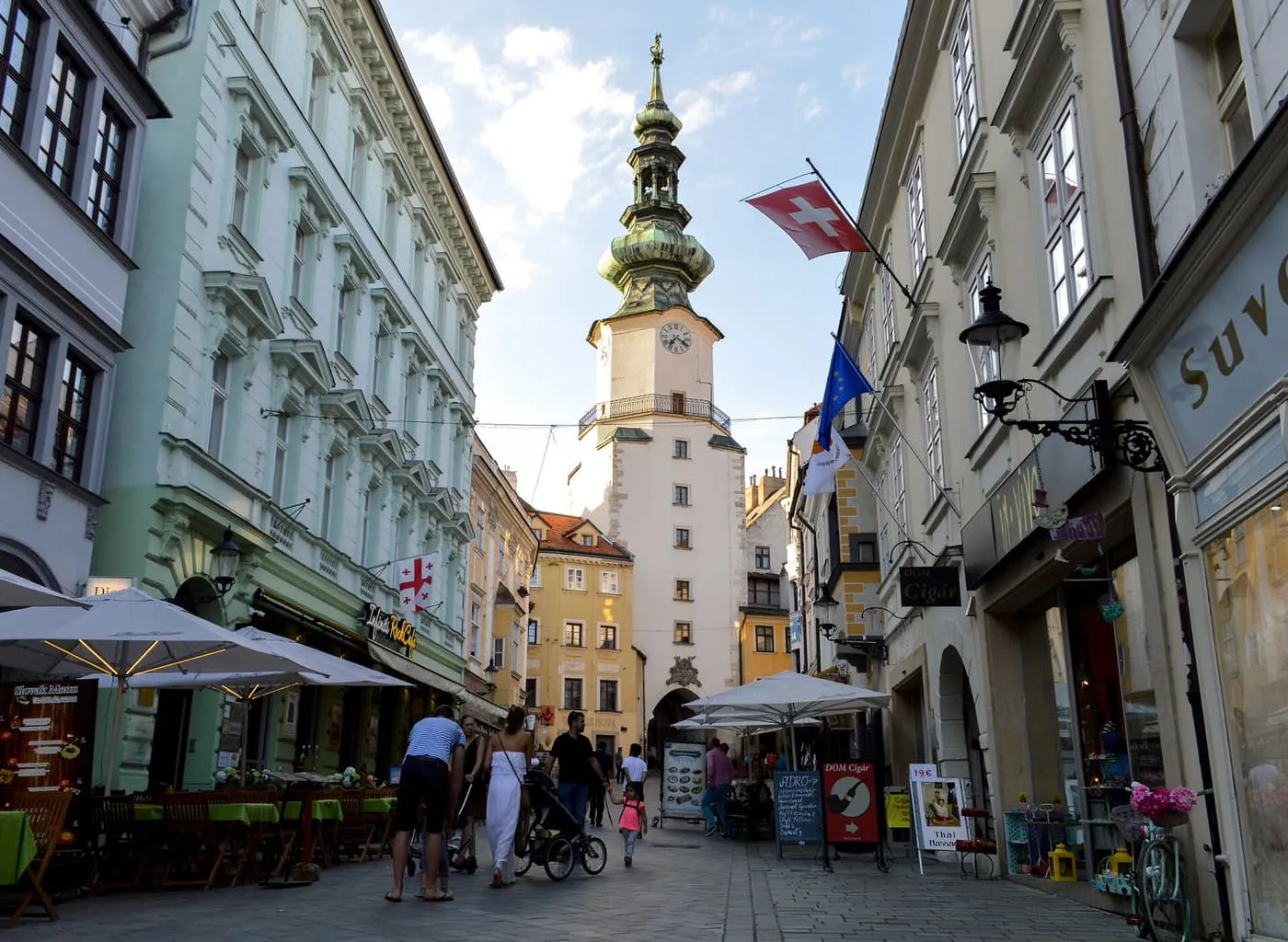 Michael's Gate tower with its green copper dome at the end of a street lined with café tables