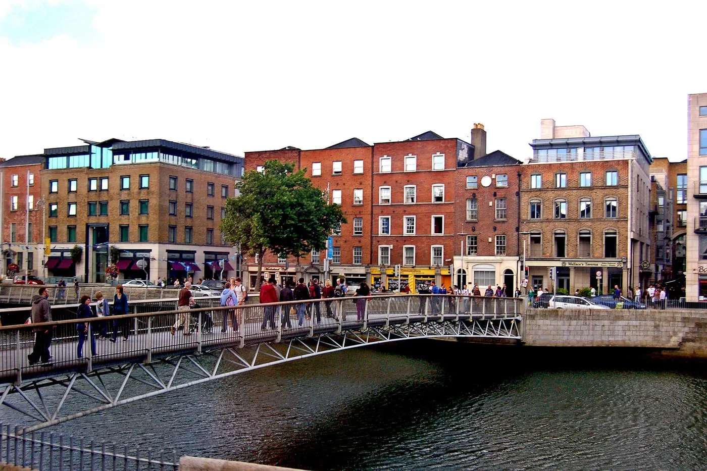 Pedestrians on the Millennium Bridge over the Liffey, with brick buildings along Ormond Quay Lower behind