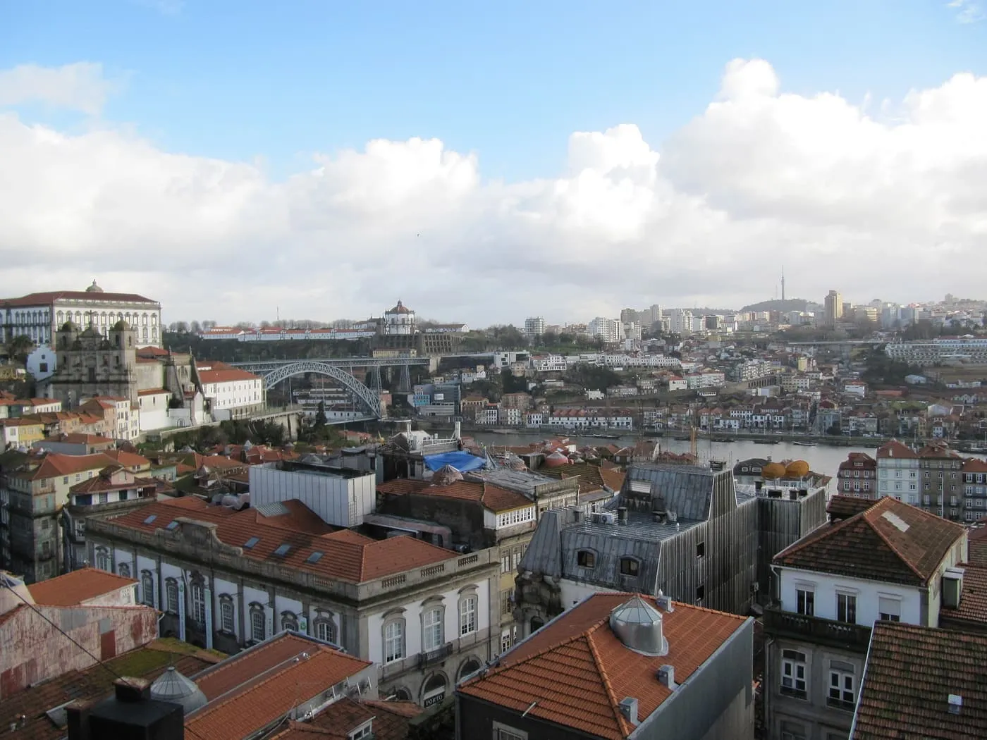 Terracotta rooftops of the old town stepping down towards the Douro, with the Dom Luís I bridge in the distance