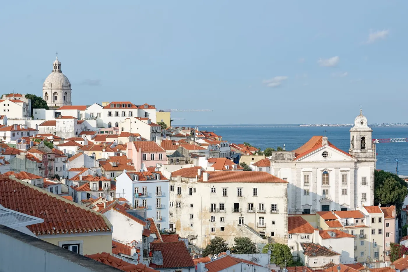 Alfama's red roofs from the Miradouro de Santa Luzia, with the dome of the National Pantheon on the left, the church of Santo Estêvão on the right and the Tagus beyond