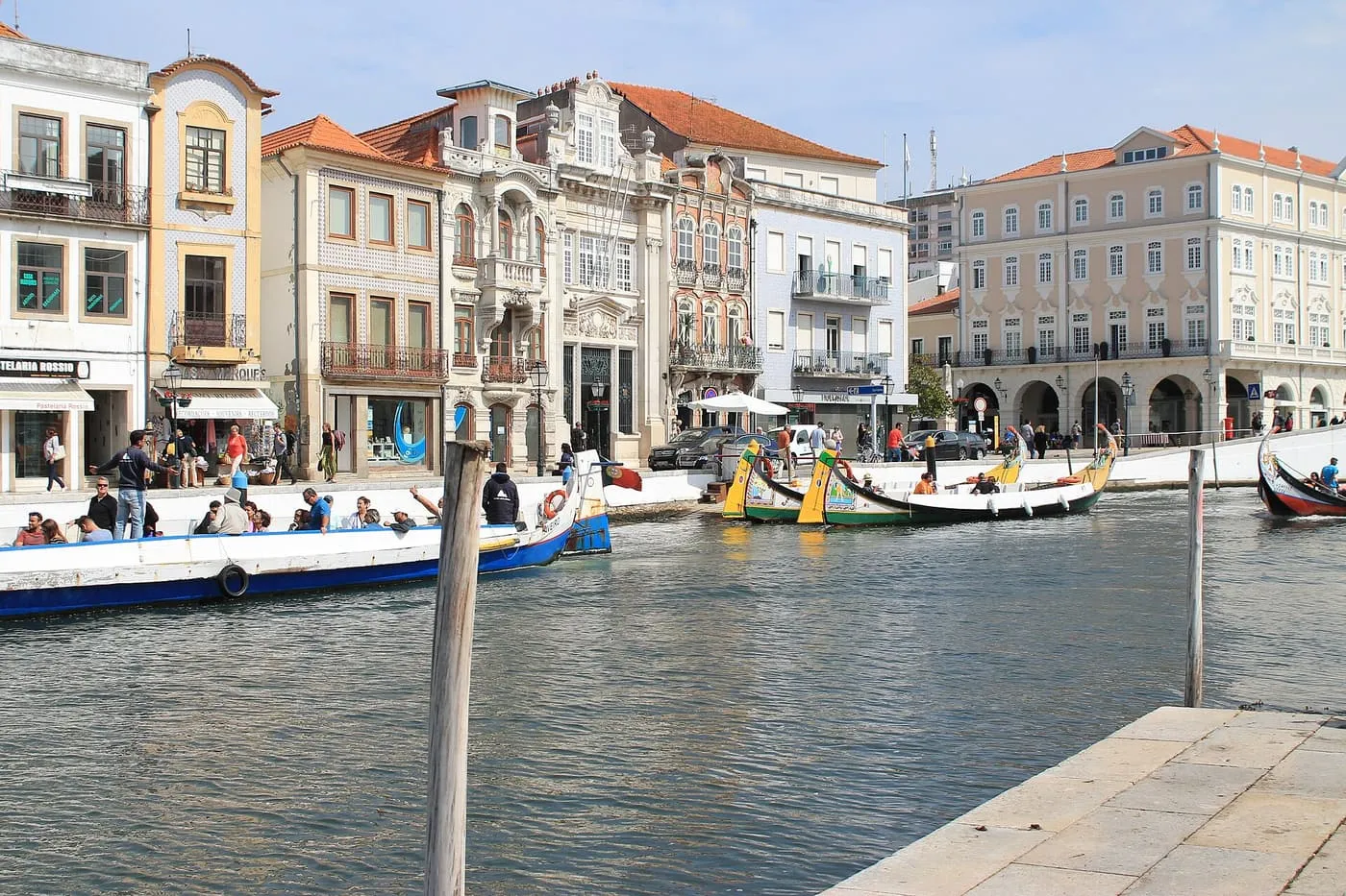 Painted moliceiro boats on the Central Canal in Aveiro, with a row of tiled and Art Nouveau buildings along the quay