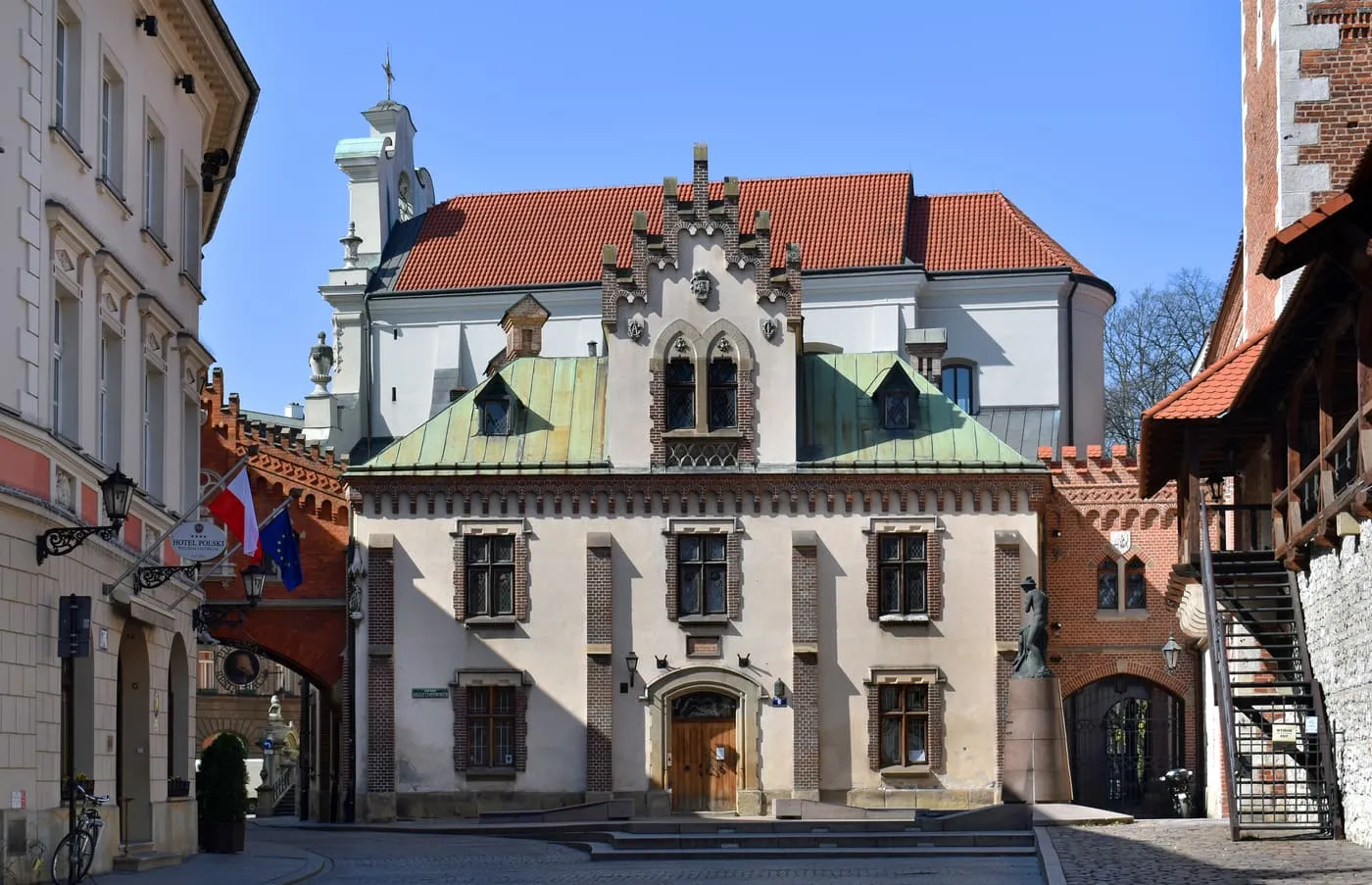 The Monastery building of the Czartoryski Museum on ul. Pijarska, a cream building with a stepped gable and a copper roof, beside a red-brick archway