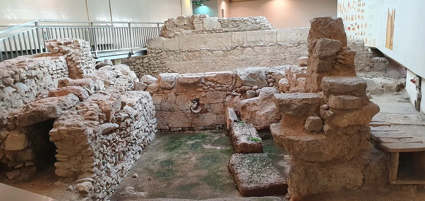 Excavated stone walls and foundations on display inside Monastiraki metro station, with a display panel on the right
