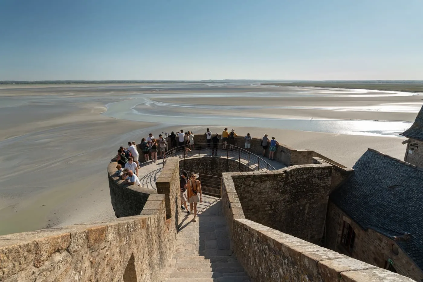 Visitors on a round tower of the ramparts above the bay's sands at low tide