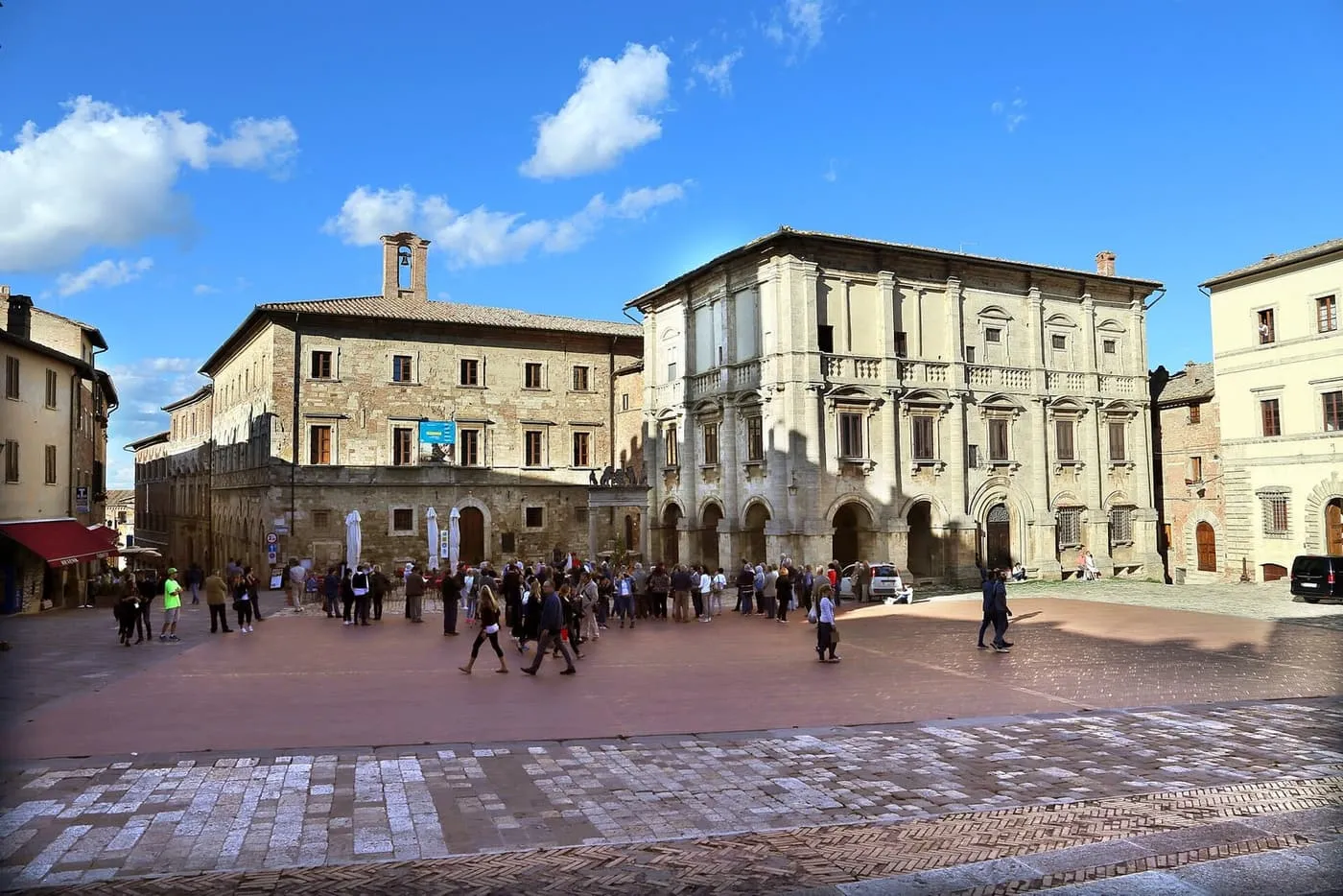 Piazza Grande in Montepulciano, with palazzi on two sides and visitors crossing the brick-paved square