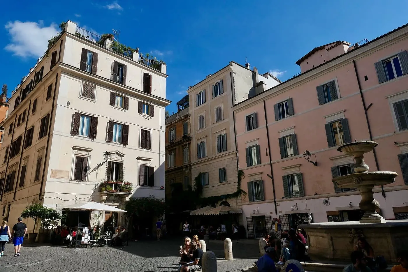 Piazza della Madonna dei Monti in Monti, with a fountain, café tables and pastel apartment buildings