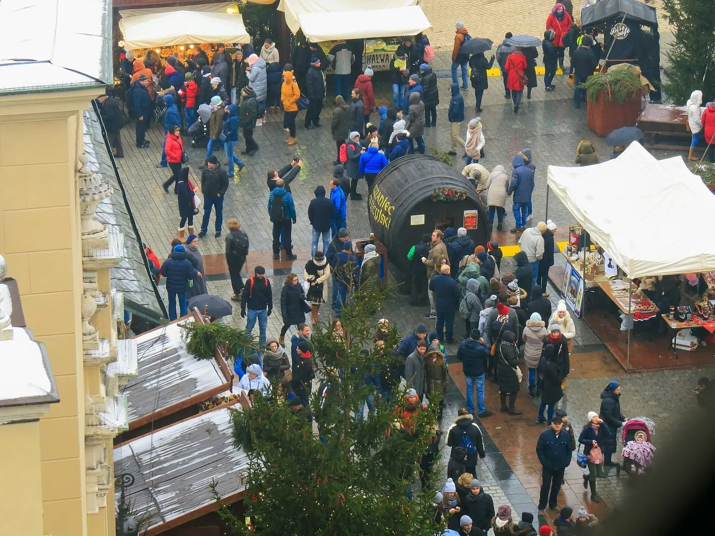 Crowds among Christmas market stalls on the Main Market Square seen from above, with a large barrel stall labelled grzaniec galicyjski