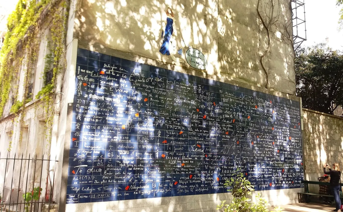 The Mur des je t'aime, a wall of dark blue enamelled tiles with "I love you" written in many scripts, in a small square with trees