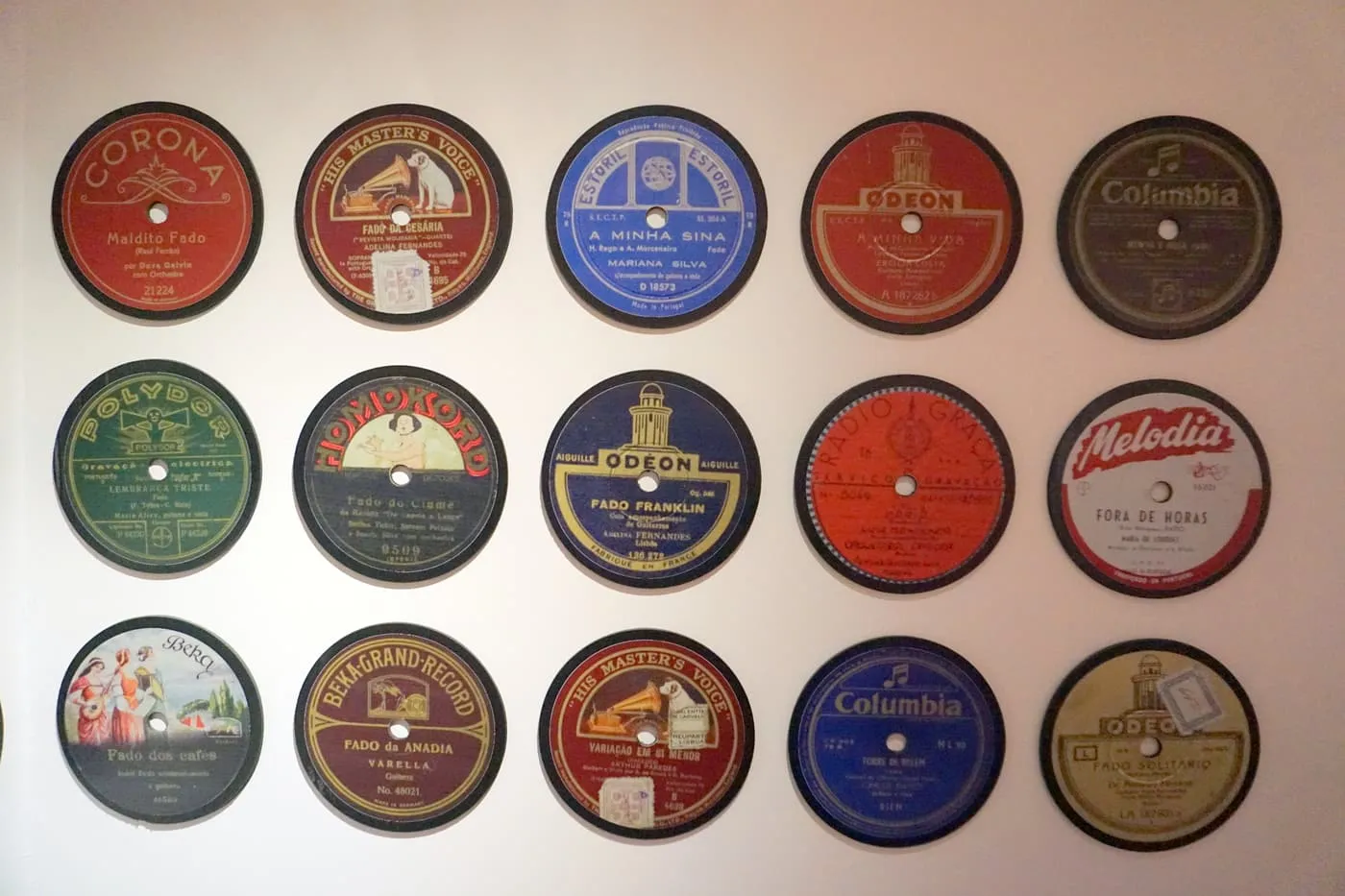 Rows of old 78 rpm records on a white wall, with labels from Odeon, Columbia and Regal