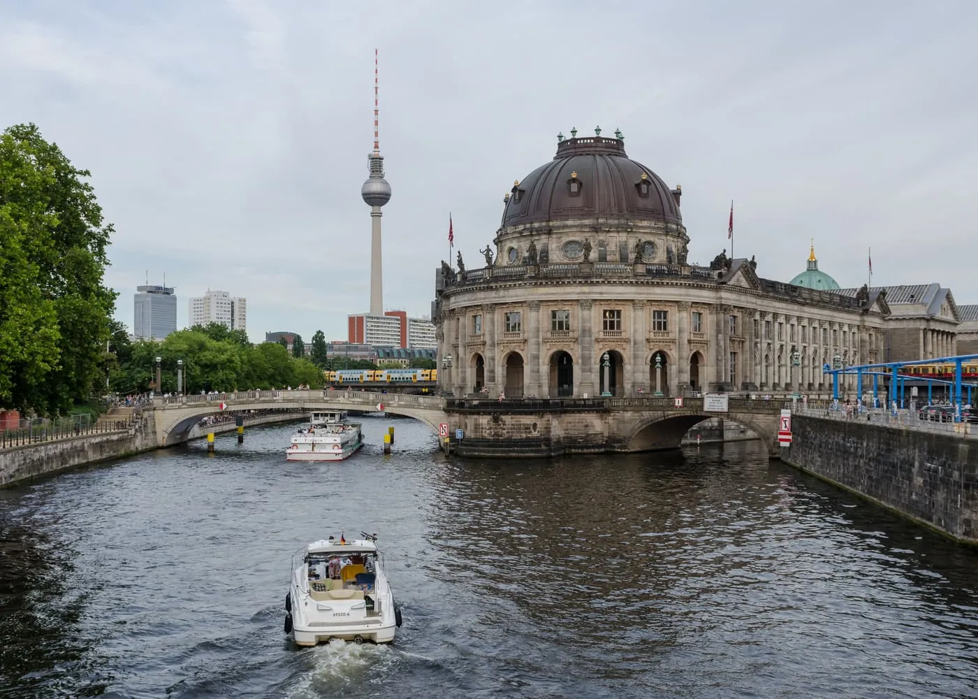 The Spree with the Bode-Museum and its dome at the tip of Museum Island, the TV Tower behind and a pleasure boat on the water