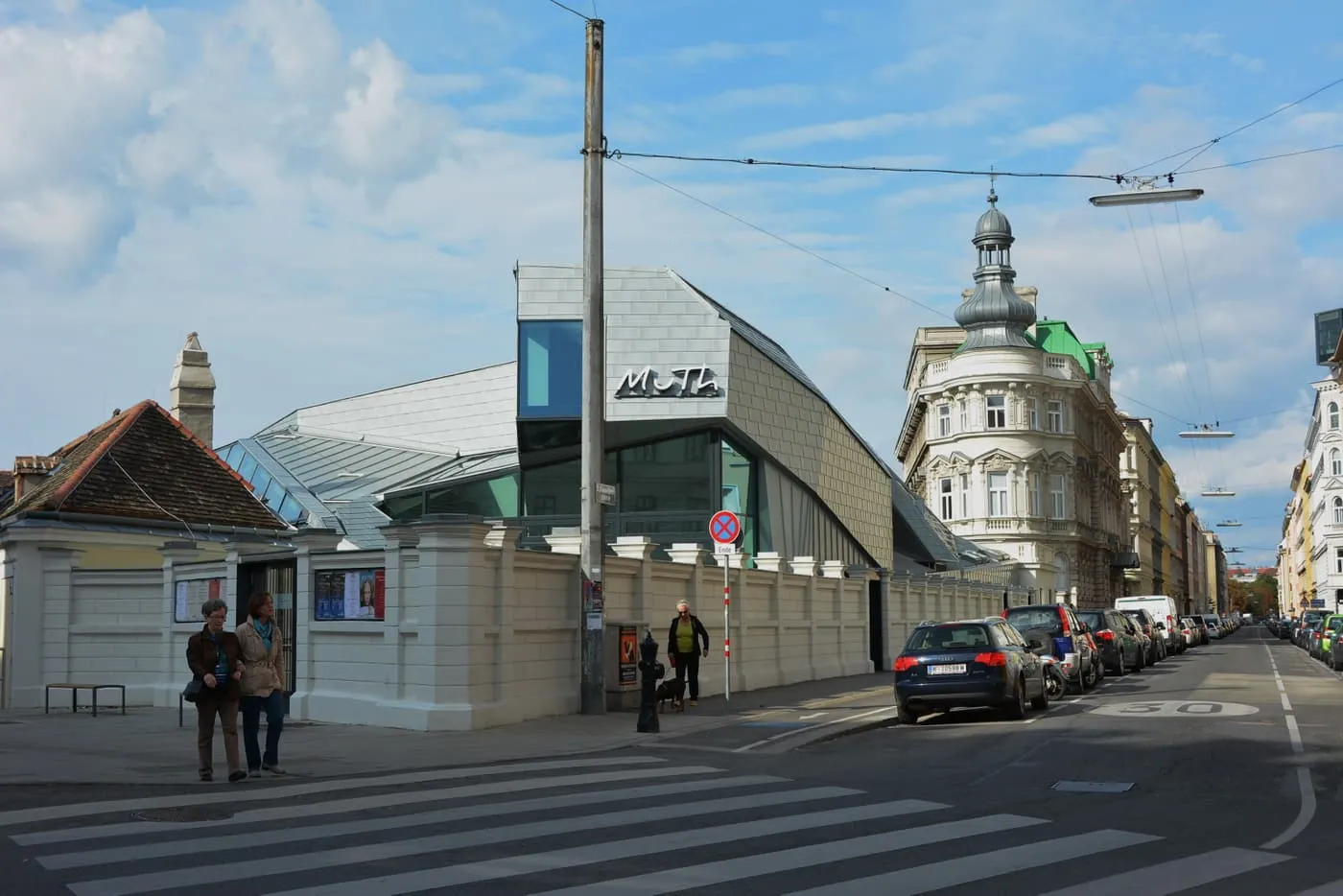 The MuTh concert hall, a low building with a faceted metal and glass roof and MuTh lettered above a white wall