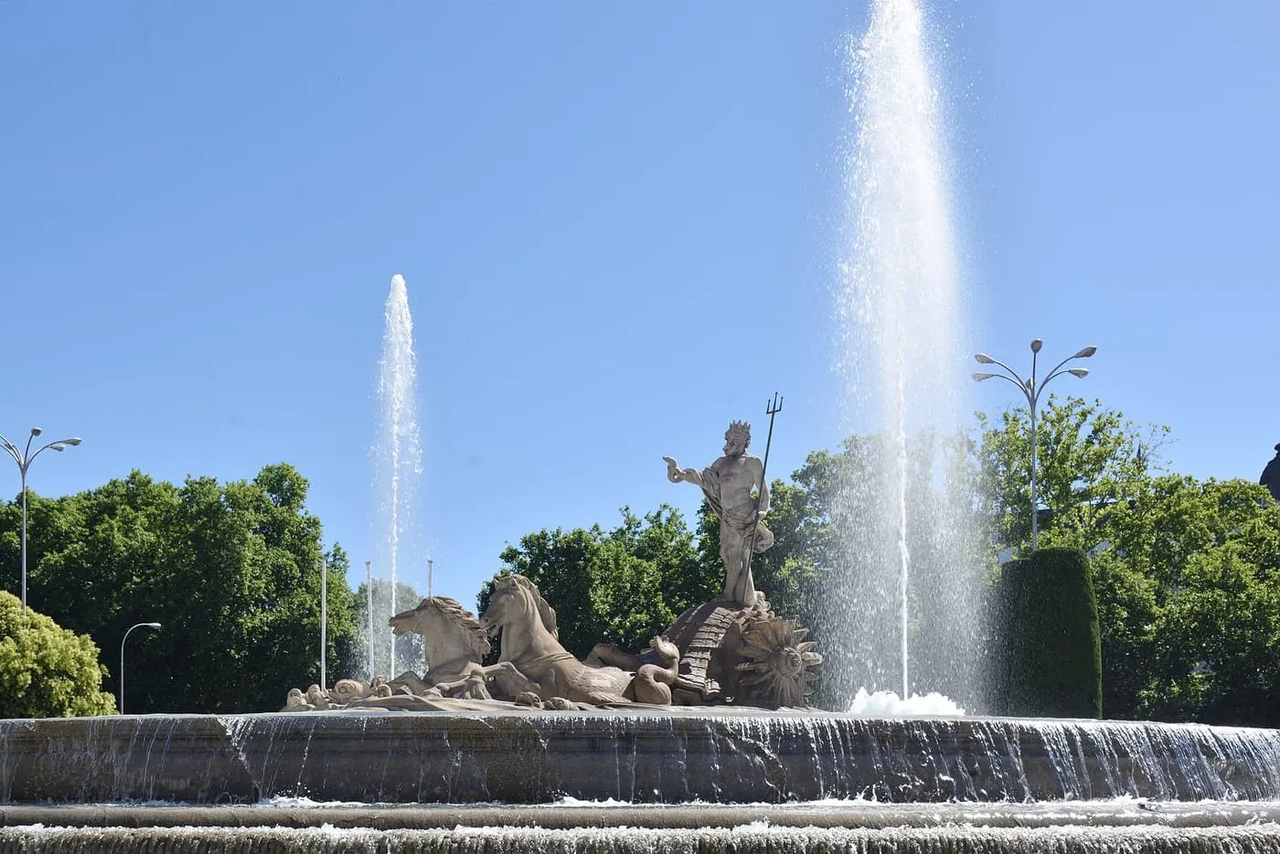The Neptune Fountain in Madrid, with Neptune in a shell chariot drawn by two sea horses, jets of water rising either side and a low waterfall round the basin