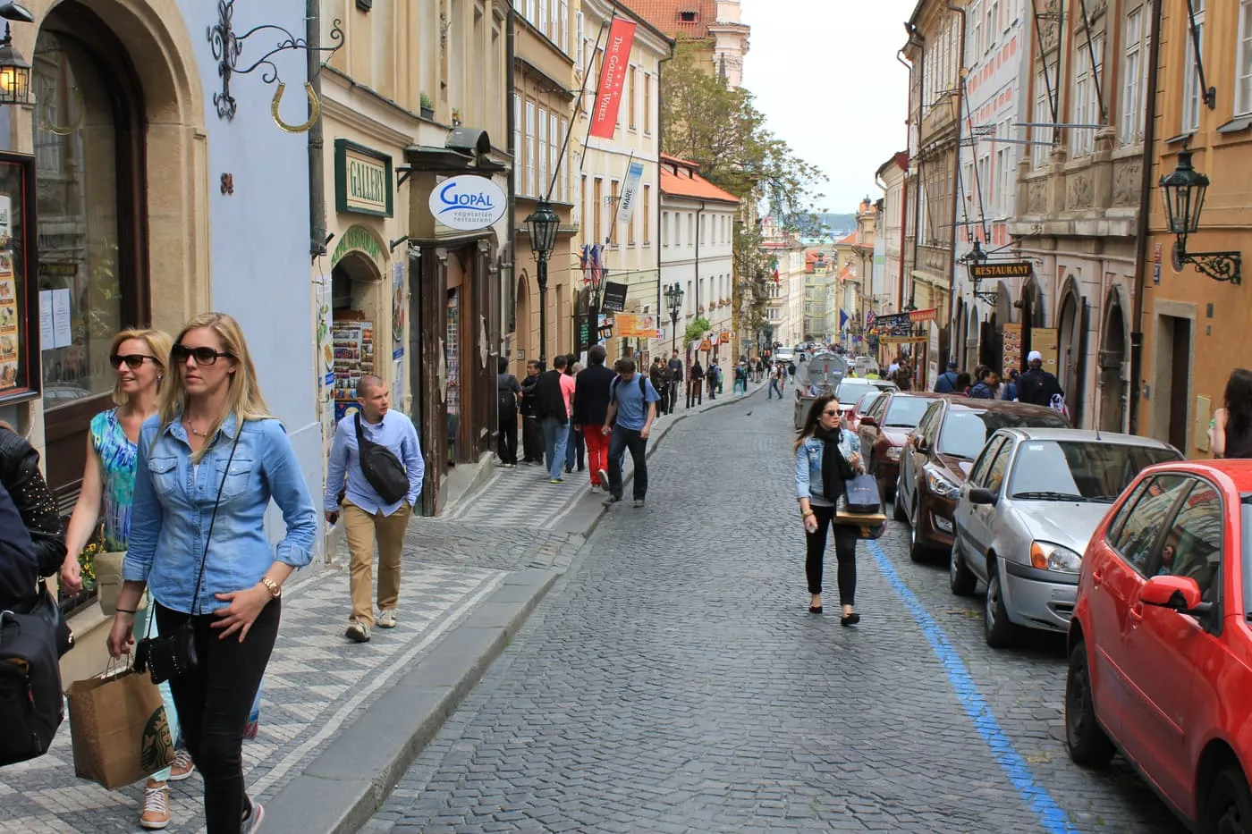 Pedestrians on the cobbled slope of Nerudova street in Malá Strana, lined with painted town houses