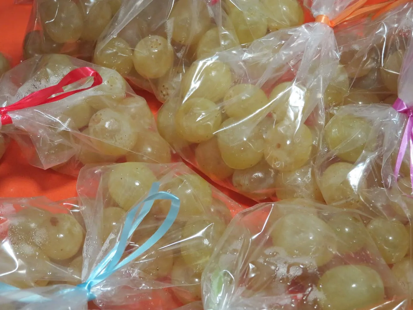 Green grapes tied up in small clear bags with red, blue, pink and orange ribbons