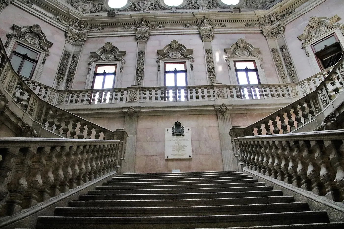 The granite Noble Staircase of the Palácio da Bolsa, with stone balustrades rising to a first-floor gallery