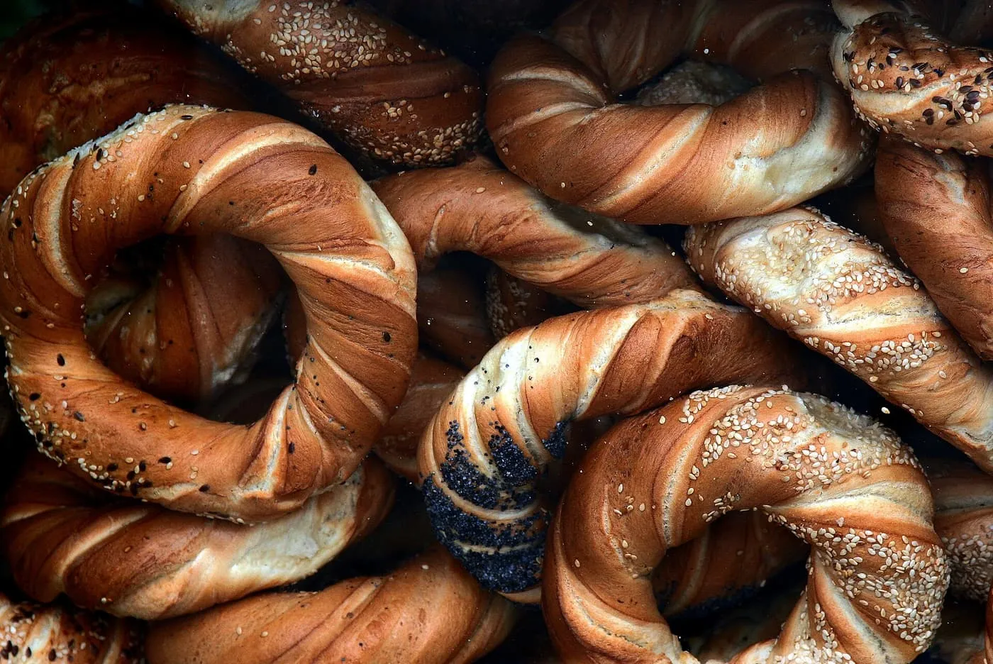 A heap of golden-brown bread rings topped with sesame and poppy seeds