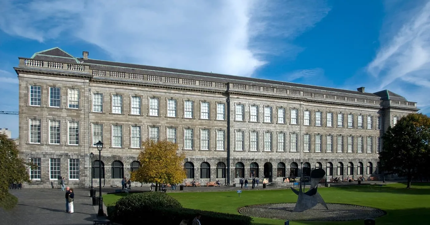 The long stone front of the Old Library at Trinity College Dublin, with a lawn and a sculpture in front