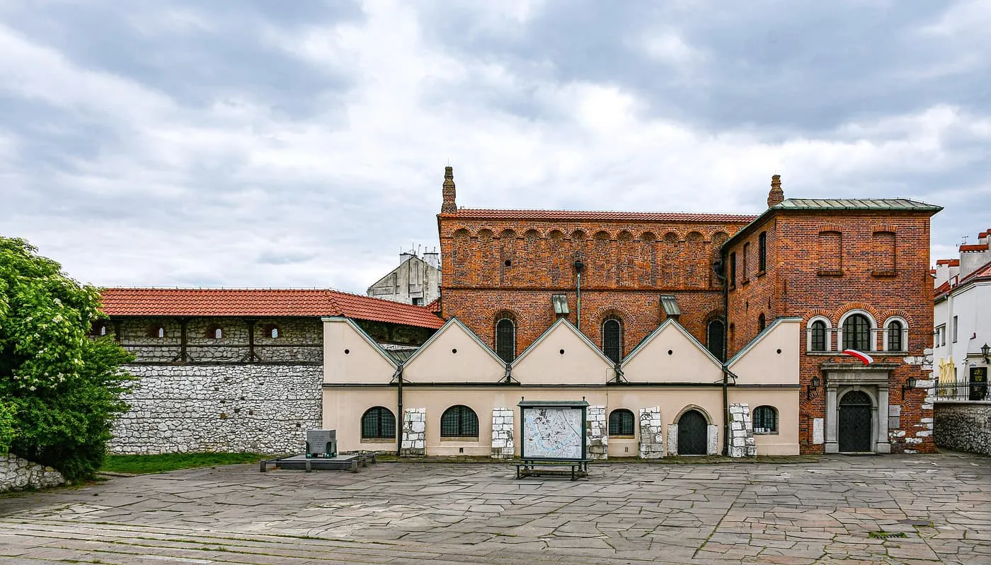 The red-brick Old Synagogue behind a low white wall on ul. Szeroka under a cloudy sky