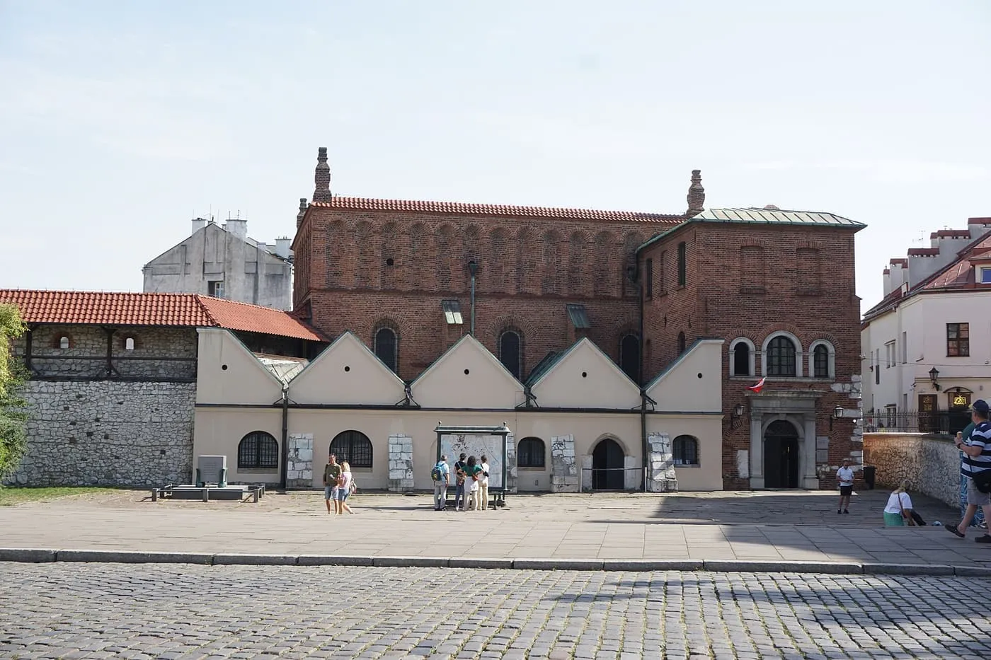 The red-brick Old Synagogue with a row of white gables along its front, seen across Szeroka Street