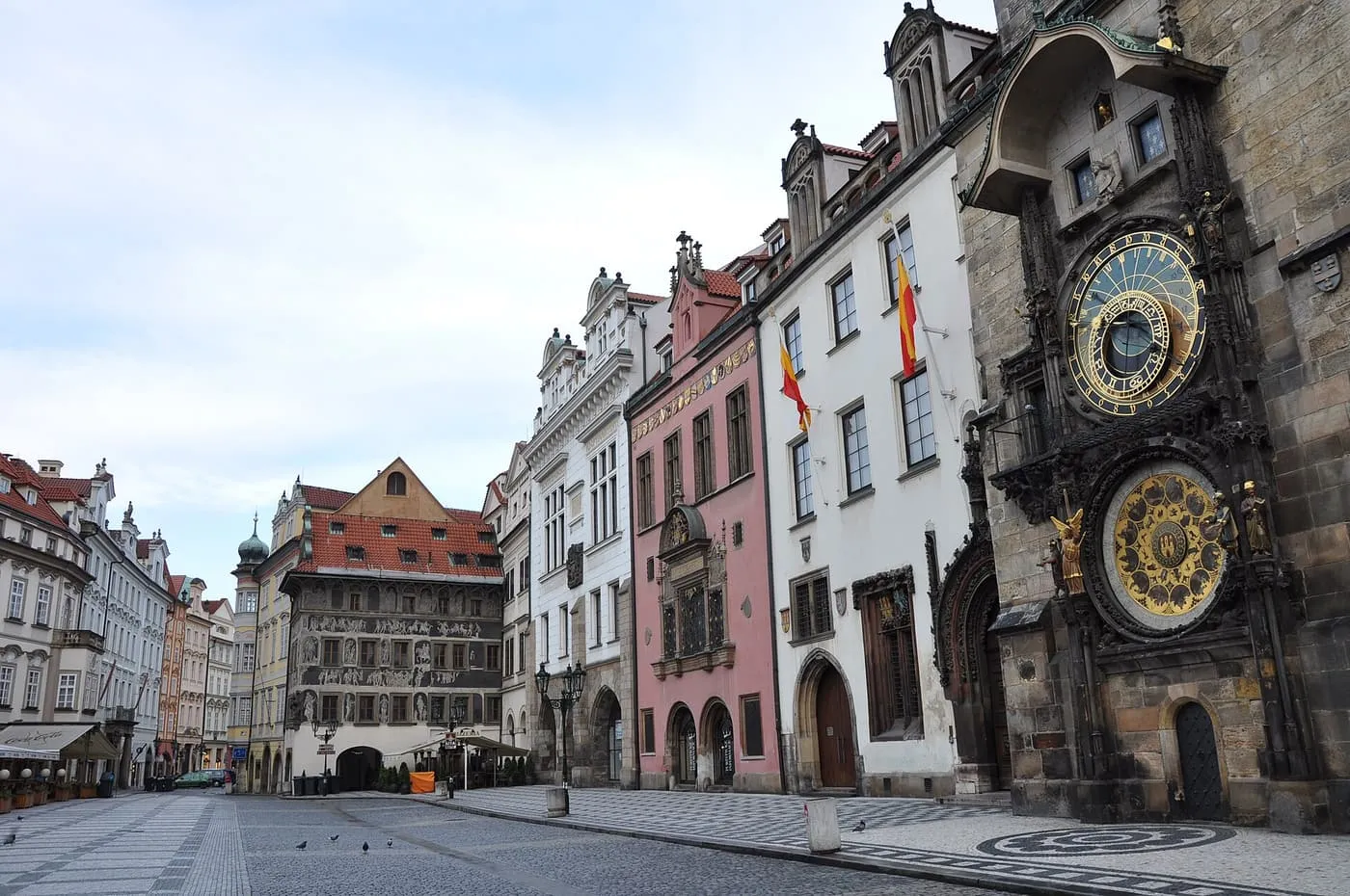 The Astronomical Clock on the wall of the Old Town Hall, beside a row of pastel Gothic and Baroque houses on Old Town Square