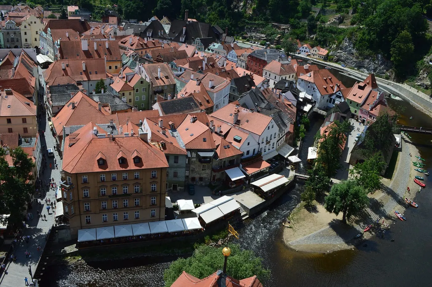 Looking down on the orange roofs of Český Krumlov's old town, the bend of the Vltava river and canoes on its bank