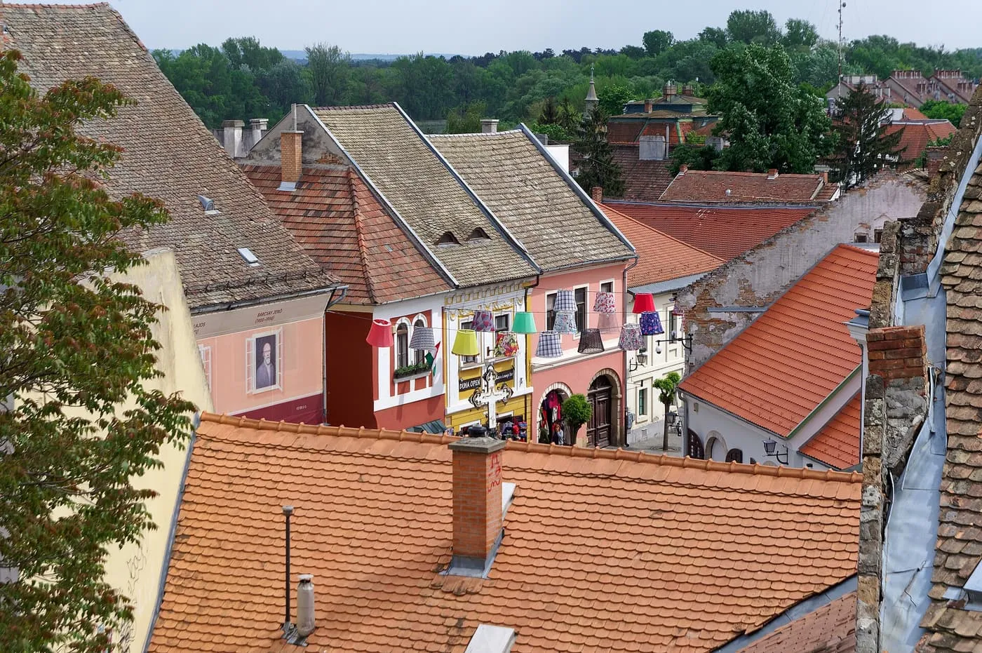 Terracotta roofs and painted house fronts in Szentendre's old town, with paper lampshades hung across a street