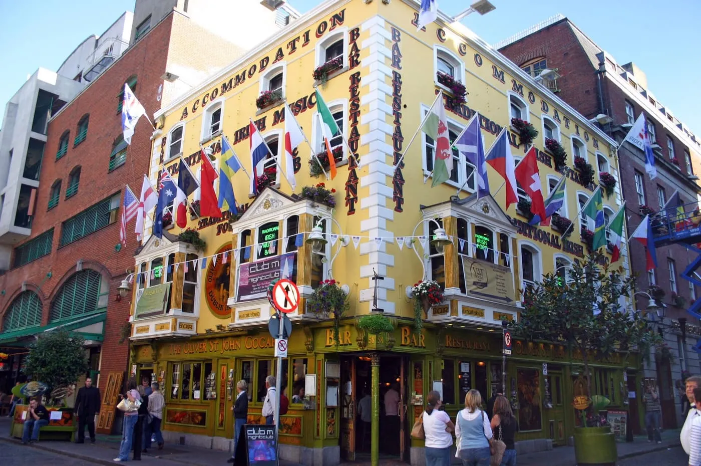 The yellow corner front of the Oliver St John Gogarty pub on Fleet Street, with flags and lettering advertising traditional Irish music