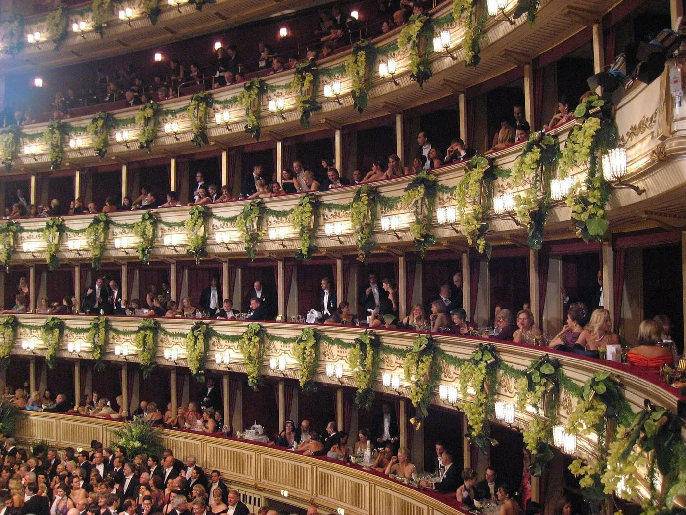 The tiers of boxes in the State Opera on ball night, hung with green garlands and filled with guests in evening dress