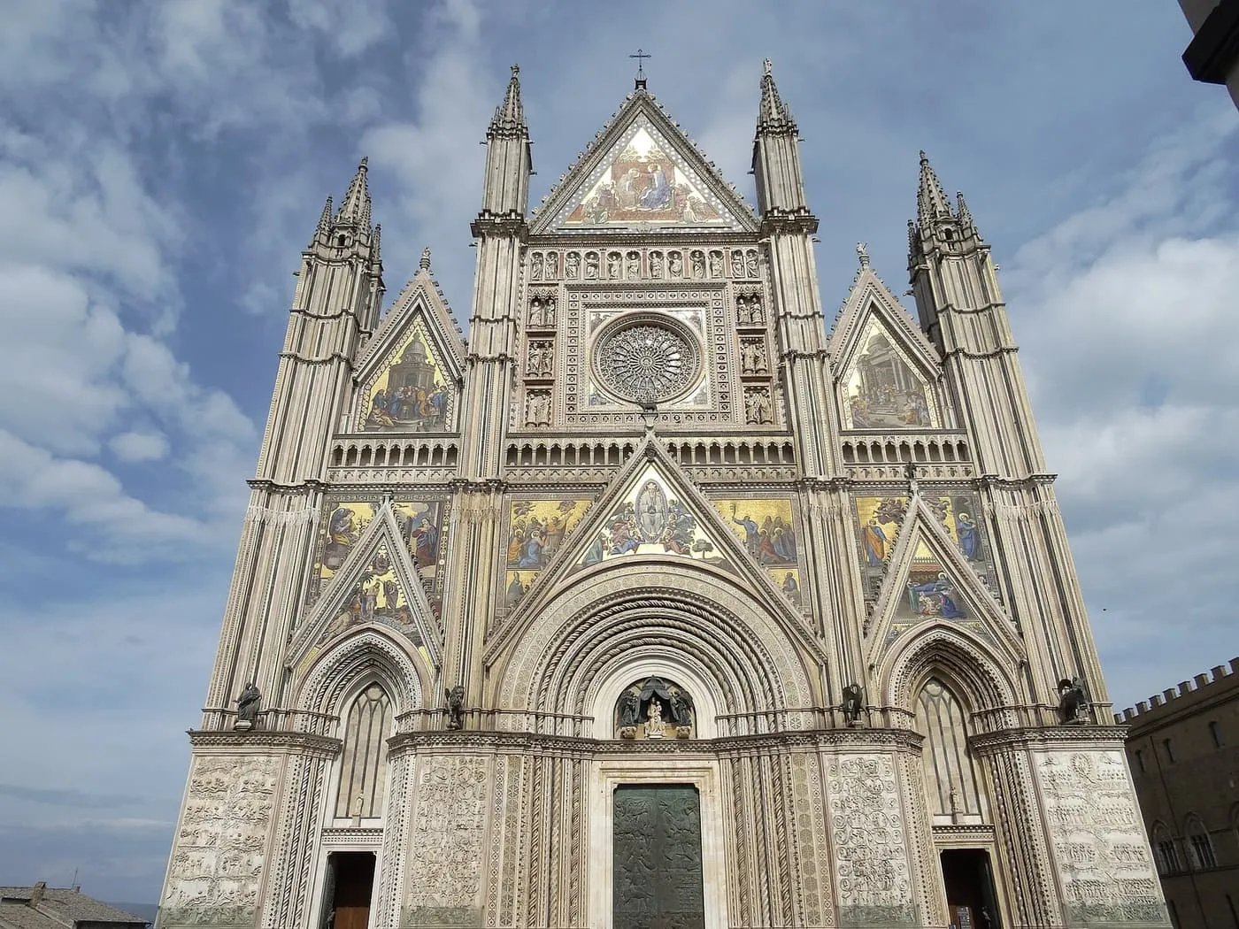 The Gothic facade of Orvieto Cathedral, with gold mosaic panels and a central rose window